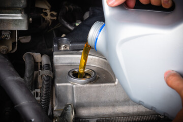 Mechanic in service to repair the car, refueling and pouring from bottle to change lubricant oil at maintenance repair service station, Energy fuel automotive concept