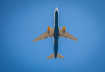 Plane flies in the sky. Bottom view. Takeoff and landing. Arrival and departure. Passenger plane isolated on blue background. Airplane flying. Travel by air transport. Aircraft copy space.