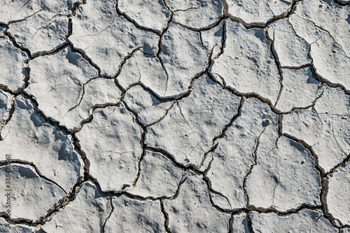 White soil cracked from the drought, top view. Background and texture to illustrate global environmental and climate change issues