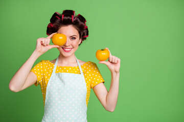 Sticker - Photo of cute charming funny young girl roller hairstyle beaming smiling hold two tomatoes cover eye tease hungry children wear dotted apron shirt isolated green color background