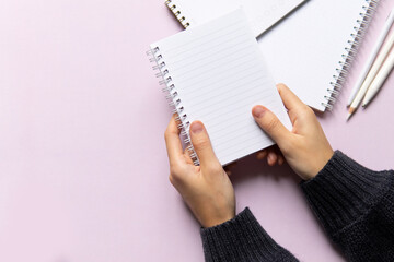 business composition with notebooks and pens on a pink background with a place to write. Business concept with hands holding notepad, writing text