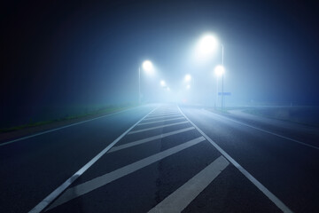 Wall Mural - Panoramic view of the illuminated new highway in a fog at night, street lights close-up. Moonlight. Dark urban scene. Europe. Transportation, logistics, travel, tourism, road trip, freedom, driving