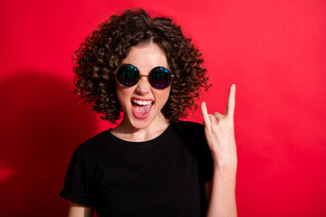 Wall Mural - Photo portrait of girl showing rock goat sign isolated on vivid red colored background