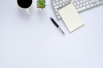 Top view above of White office desk table with keyboard, notebook and coffee cup with equipment other office supplies. Business and finance concept. Workplace, Flat lay with blank copy space.