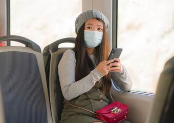 Canvas Print - new normal traveling - young attractive and pretty Asian Japanese woman in face mask sitting on railcar by window using internet mobile phone in the train relaxed