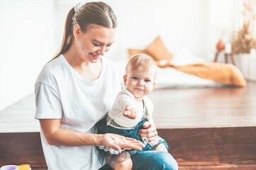 Wall Mural - Mom and baby are sitting at home and smiling cheerfully