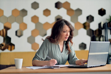 Young woman working from home office. Freelancer using laptop and the Internet. Workplace in living room.