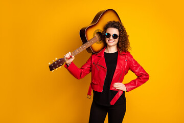 Canvas Print - Portrait of attractive cheerful wavy-haired girl musician carrying guitar isolated on bright yellow color background