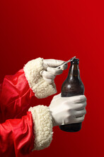 Santa Claus Opening A Beer Bottle. Coloured Background And Seletive Focus.