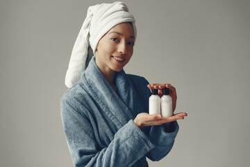 Girl in a studio. Lady with cream. Woman in a blue robe