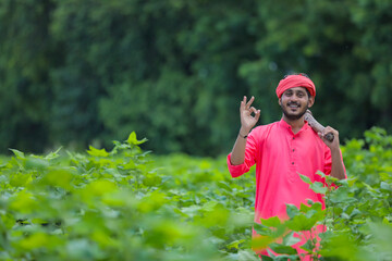 Young indian farmer holding farm equipment in hand at cotton field