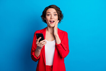 Portrait of attractive amazed cheerful brown-haired lady using device app 5g good news reaction isolated bright blue color background