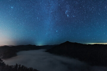 Wall Mural - a beautiful starry night in the mountains on top with beautiful scenery and fog.