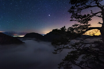 Wall Mural - A beautiful starry night in the mountains on top with beautiful scenery and fog.