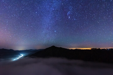 Wall Mural - a beautiful starry night in the mountains on top with beautiful scenery and fog.