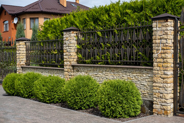 Wall Mural - Iron wrought-iron fence between decorative brick columns in front of a residential building.