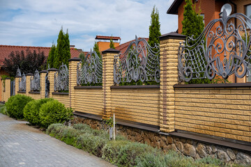 Iron wrought-iron fence between decorative brick columns in front of a residential building.