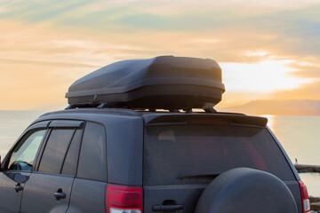 Wall Mural - Off-road Vehicle with an Autobox on the roof by the Sea at Sunset.