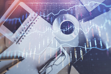 double exposure of financial graph hologram over desktop with phone. top view. mobile trade platform