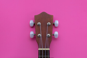 Closeup shot of a ukulele headstock on a pink background