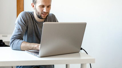 young happy man working at laptop, copy space