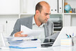 © JackF - Portrait of male worker in the office sitting at the table with documents