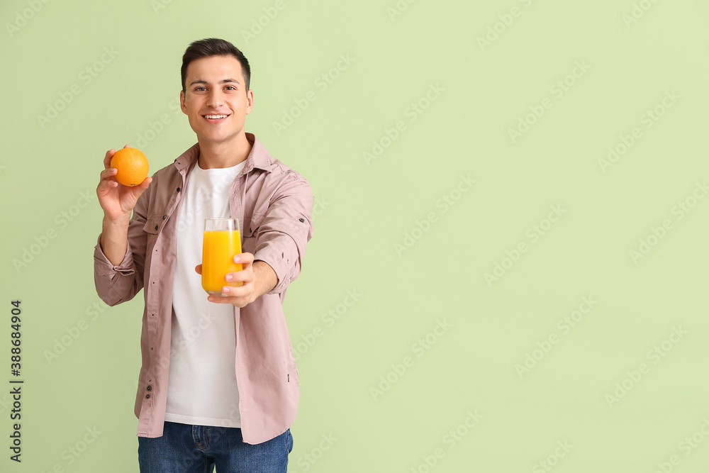 Handsome man with orange juice on color background