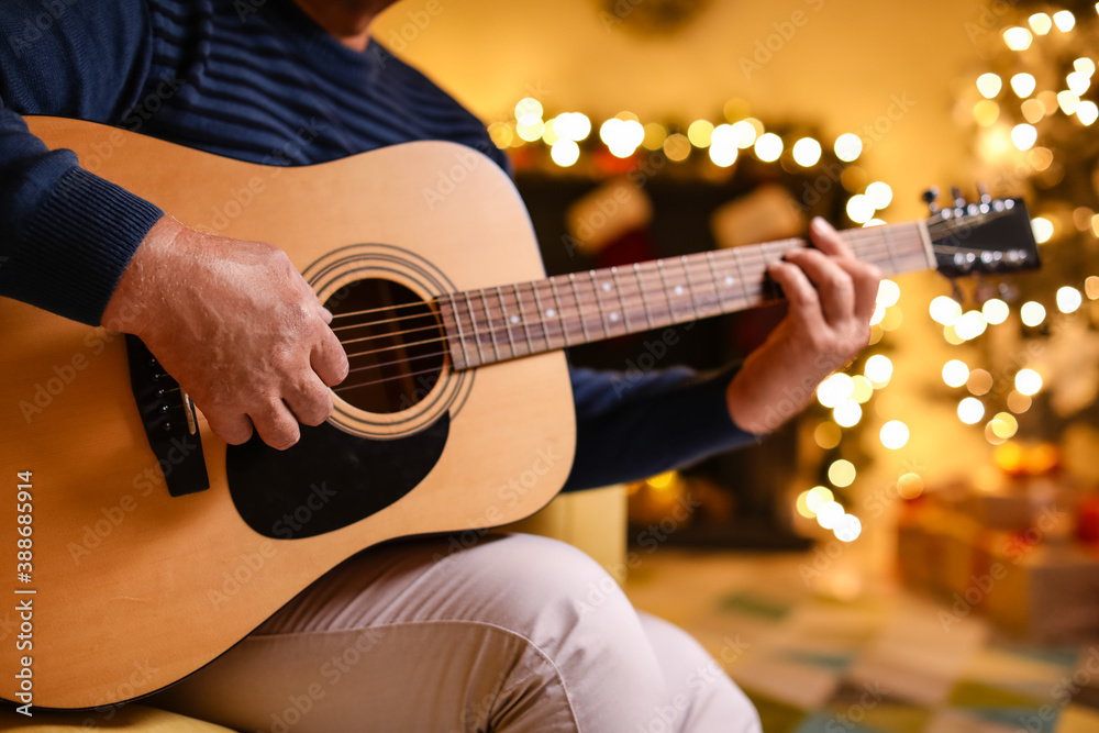 Mature man playing guitar at home on Christmas eve
