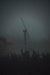 windmill standing tall in a field of fog