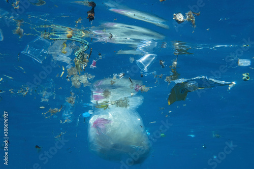 Plastic and other debris floats underwater in blue water. Plastic garbage polluting seas and ocean
