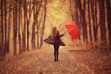 young woman dancing in an autumn park with an umbrella, spinning and holding an umbrella, autumn walk in a yellow October park