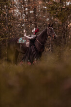 Young Woman Dressed As Mexican Symbol Of Day Of The Dead Posing In Forest With Horse