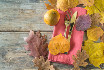 Wall Mural - Autumn holiday table setting. Table setting for Thanksgiving dinner. Golden fork and knife, napkin and autumn leaves on old non paint wooden background. Flat lay, copy space