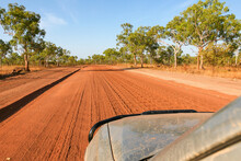 Car Traveling Along A Dusty Red Dirt Road In The Outback In The Kimberley, Shot From The Window Of The Passenger Seat Whilst Driving