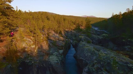 Wall Mural - Fast moving water falls and rapids of a glacial river at sunset. Aerial fly over