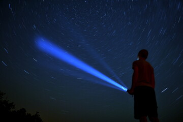 person in the night space holding flashlight