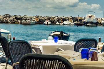 Elegant lunch restaurant, overlooking the sea and boats. Restaurant tables prepared waiting for customers, stock photo