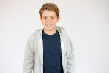 Photo of adorable young happy boy looking at camera over white background.