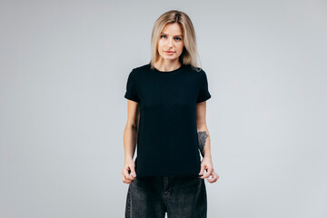 Stylish blonde girl wearing black t-shirt posing in studio