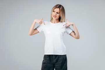 Wall Mural - Stylish blonde girl wearing white t-shirt posing in studio