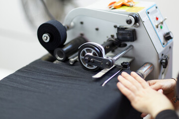 The worker is working with a tape cutter machine in a fabric factory.