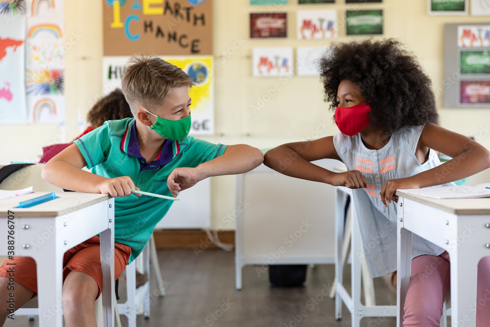 Boy and Girl wearing face masks greeting each other by touching elbows at school - obrazy, fototapety, plakaty 