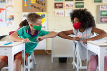 Boy And Girl Wearing Face Masks Greeting Each Other By Touching Elbows At School
