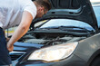© marozzau - A man looks under the hood of a car for troubleshooting.
