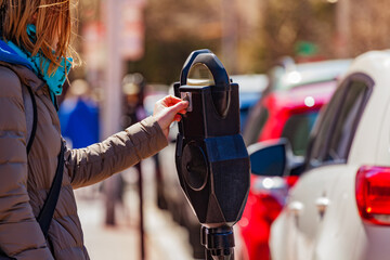 Woman pay parking on street park meter pole in the USA city