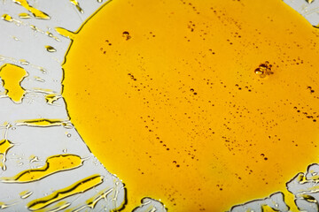 Yellow viscous liquid sunflower lecithin with bubbles on glass in the shape of a sunflower