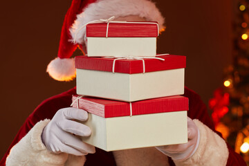 Santa holding stack of gift boxes in front of his face he bringing them to holiday