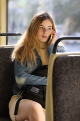 Young cute girl passenger using mobile phone in modern tram