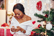 © prostooleh - Beautiful girl in a decorated room. Woman near Christmas tree. Black lady in a white blouse
