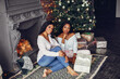 © prostooleh - Beautiful girls in a decorated room. Women near Christmas tree. Black ladies with gifts